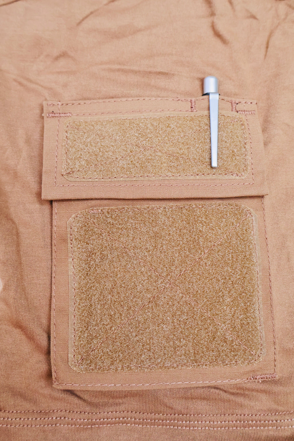 Close-up of a brown fabric with Velcro patches and a metal clip.