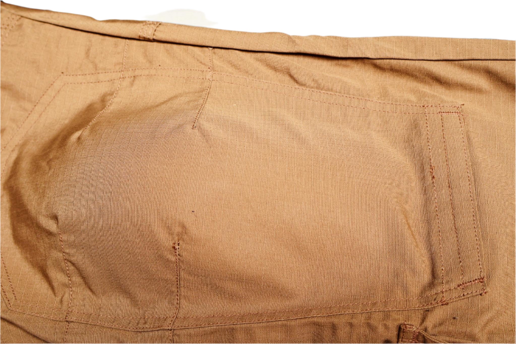 Close-up of a brown fabric Knee Pad pocket with visible texture and wear.