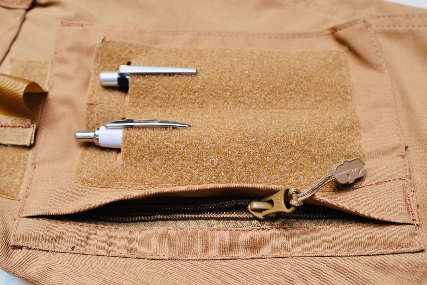 Close-up of a brown tactical pouch with various components attached.