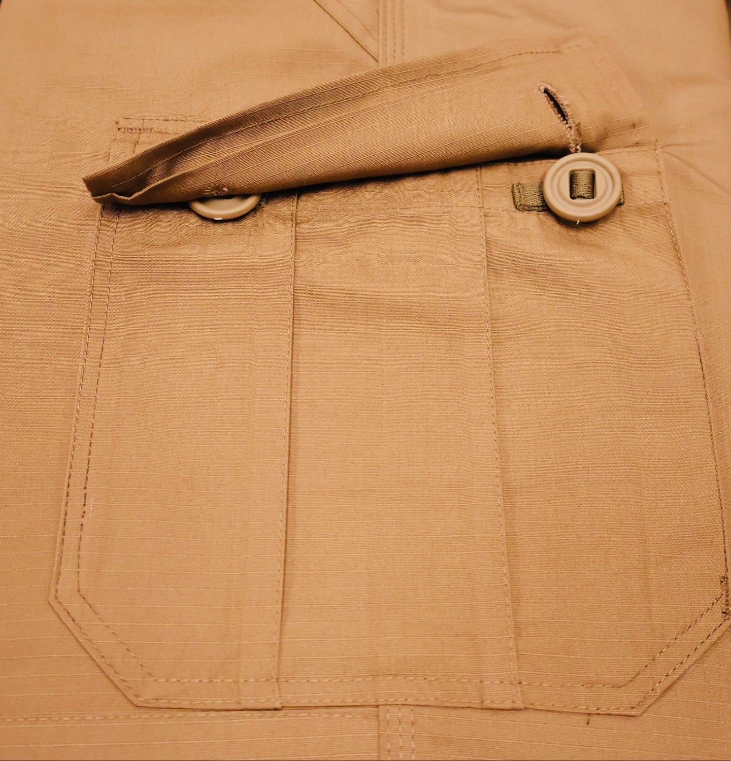 Close-up of beige pants with a pocket and button on a blurred background